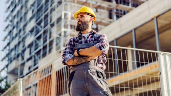modele tableau suivi chantier excel - un ouvrier de chantier croisant les bras devant un bâtiment en construction