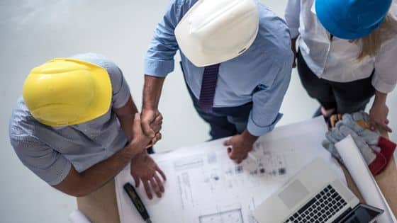certification qualibat - des professionnels du bâtiment se serrant la main devant un plan d'architecte
